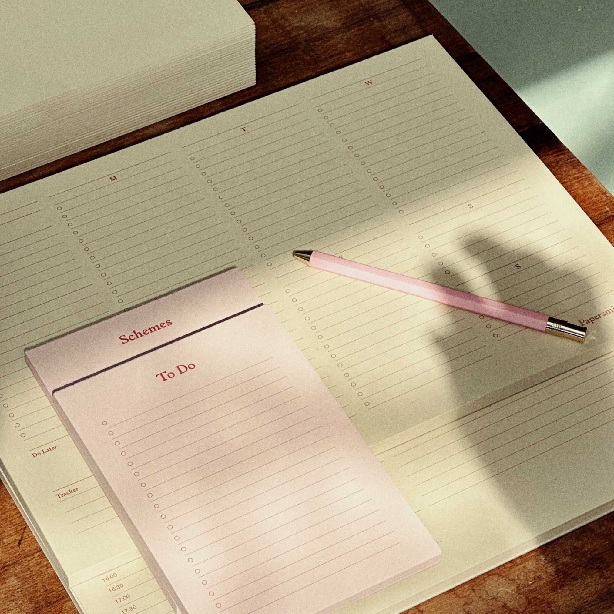 Open planner with a pink pen on a wooden surface