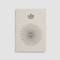 Beige book titled 'The LIFE Designer' with a starburst design on a light gray background