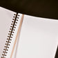 Open notebook with spiral binding on a dark surface