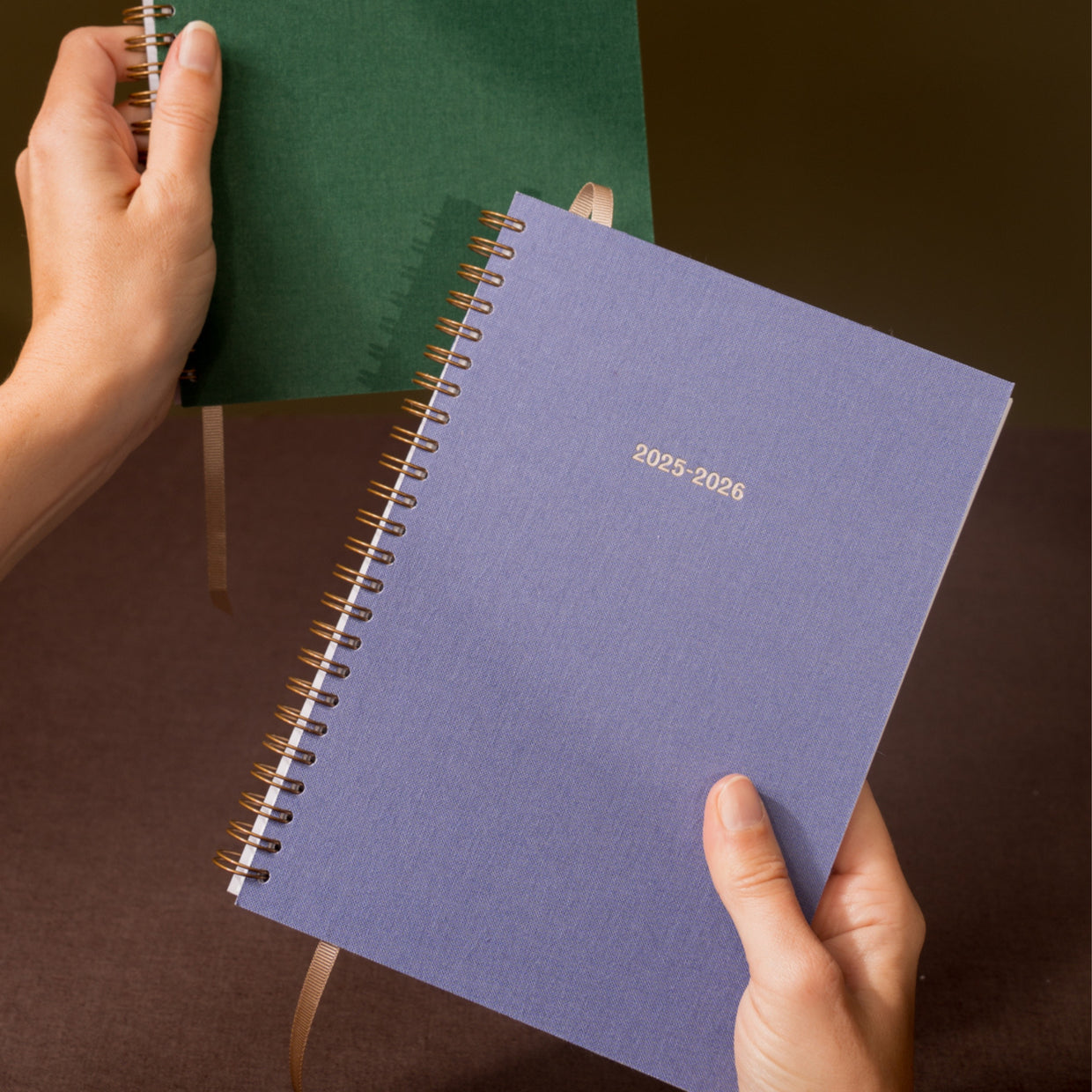 Purple planner with '2025-2026' text held by a hand against a dark background