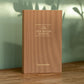 Brown journal titled 'The Five Minute Journal' by Papersmiths on a wooden surface with a blurred green background