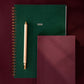 Two notebooks, one green and one burgundy, with a pen on a dark red background.