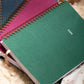 Green spiral-bound planner with '2026' on a textured surface