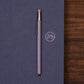 Purple pencil on a blue surface with a logo, on a wooden surface