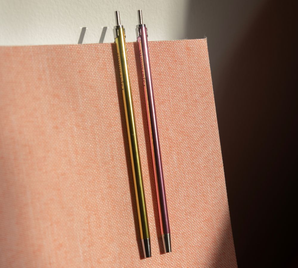 2 pocket sized pens in metallic on a coral pink notebook